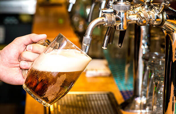 Bartender pouring beer into tall glass